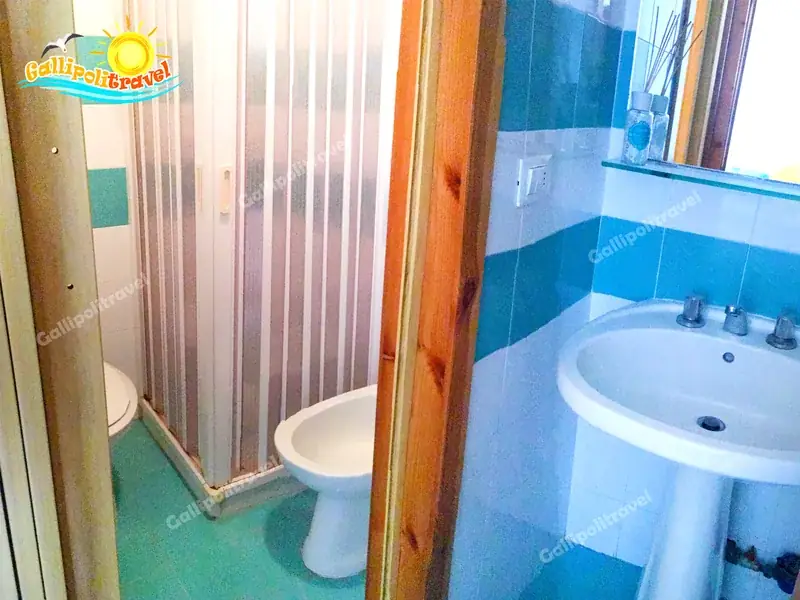 Bagno del Bilocale La Vela con piastrelle azzurre e doccia a Gallipoli