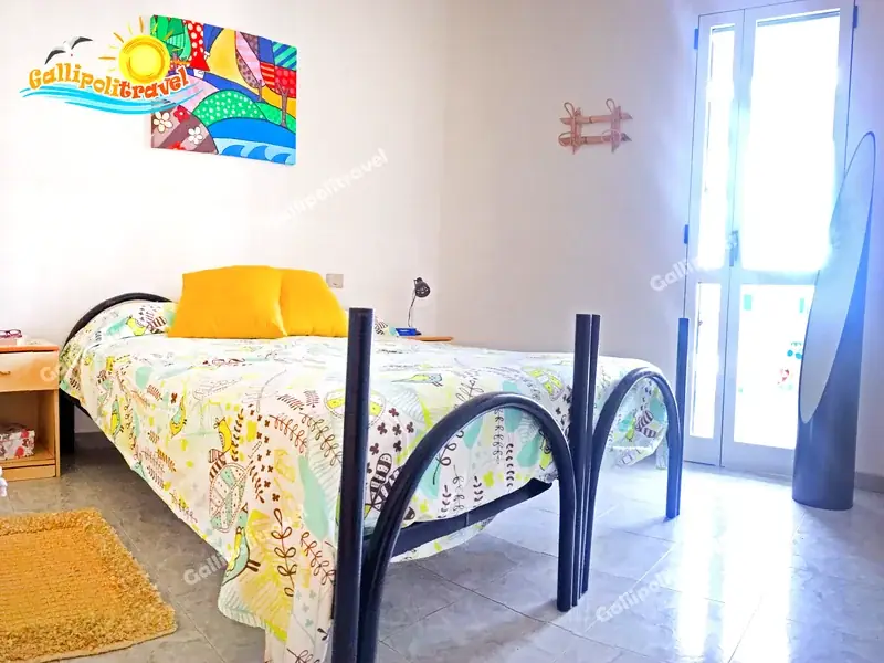Camera singola del Bilocale La Vela con quadro colorato e porta-finestra