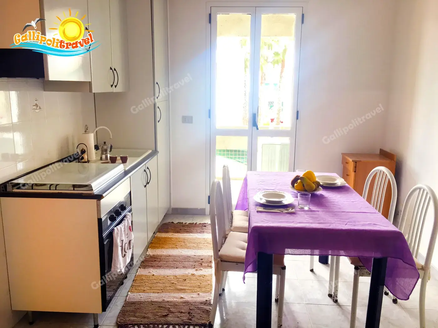 Cucina del Bilocale La Vela a Baia Verde con tavolo viola e vista palme