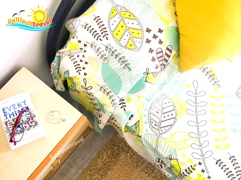 Particolare del letto del Bilocale La Vela con coperta a uccellini e comodino