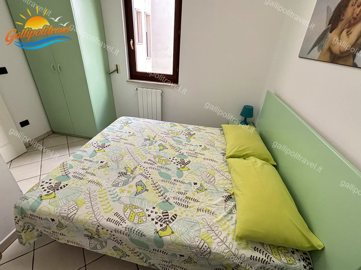 Camera da letto con armadio verde e coperta fantasia del Trilocale B2/3, Rosa Virginia Gallipoli