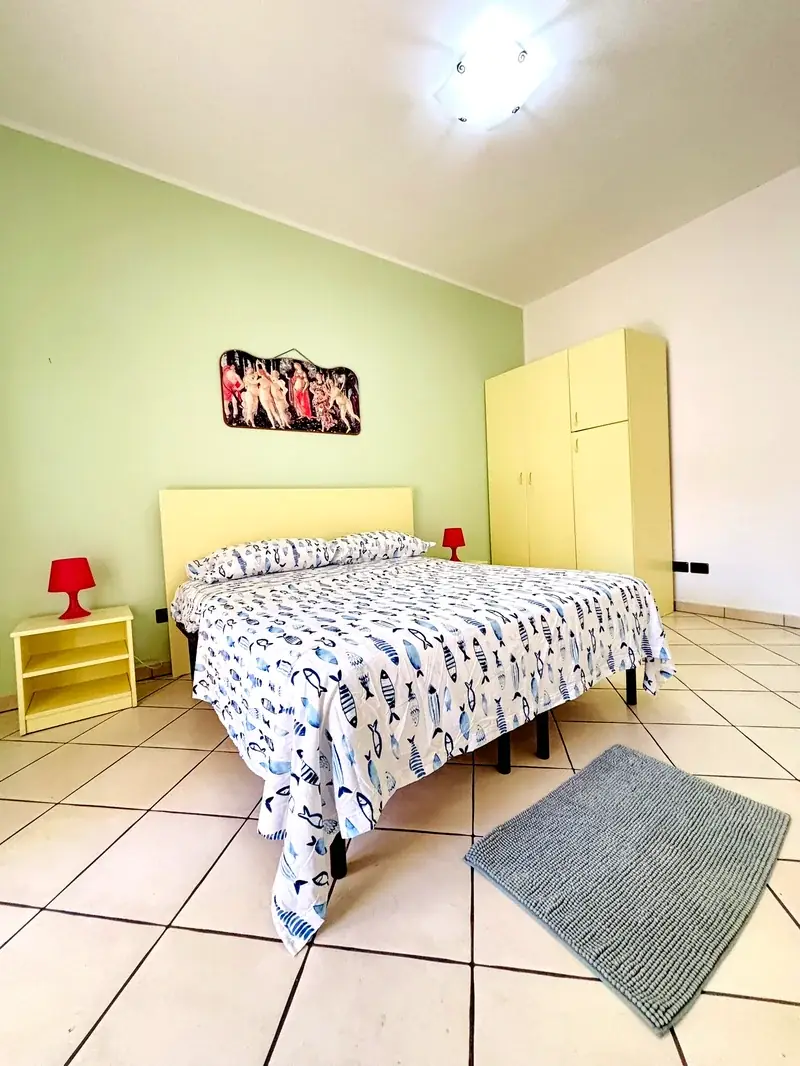 Camera matrimoniale con coperta a pesci e lampade rosse del Trilocale B2/4 Rosa Virginia