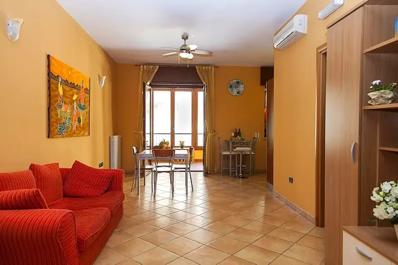 Soggiorno ampio Trilocale F1/1 con divano rosso e ventilatore