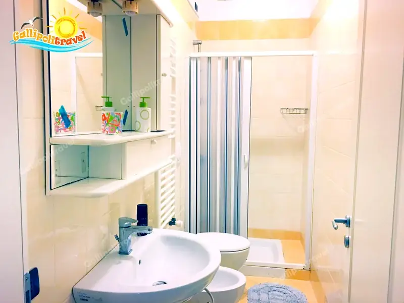 Primo bagno del Trilocale H2/2 con piastrelle beige, doccia e scaldasalviette