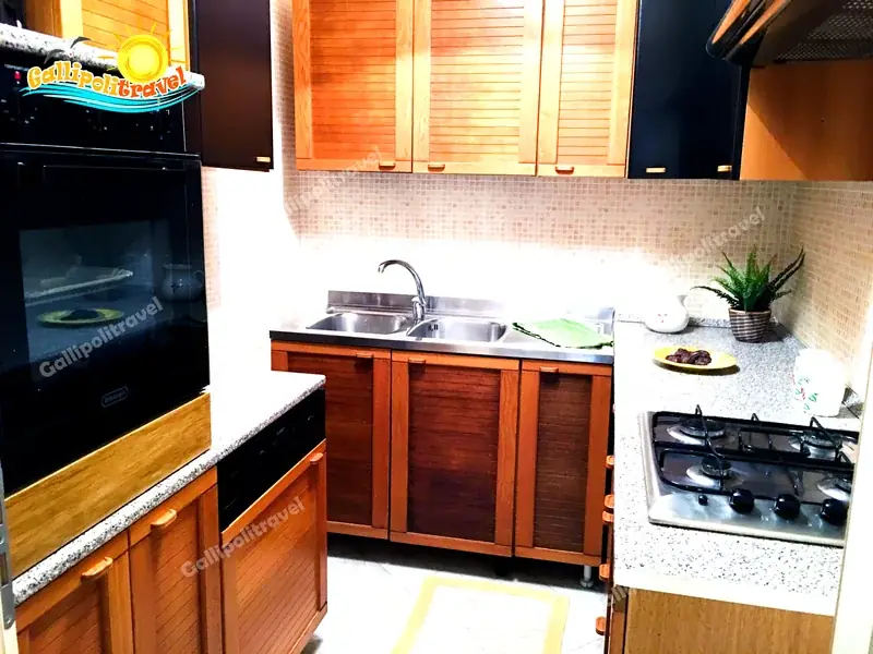 Cucina ad angolo del Trilocale H2/2 con piano in granito, forno e ante in legno