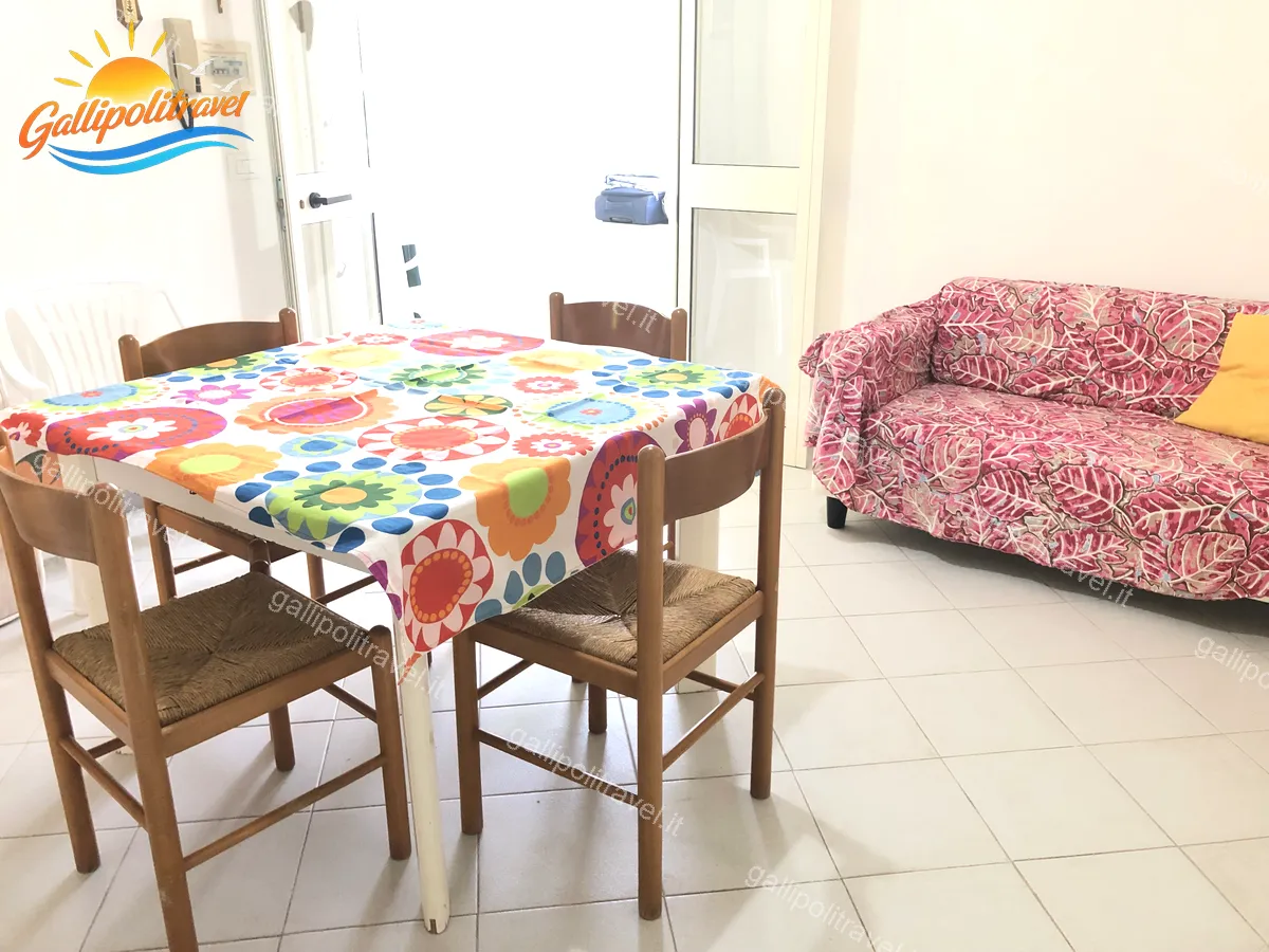 Soggiorno con tavolo e tovaglia colorata del Trilocale Tamerici 02, Baia Verde Gallipoli