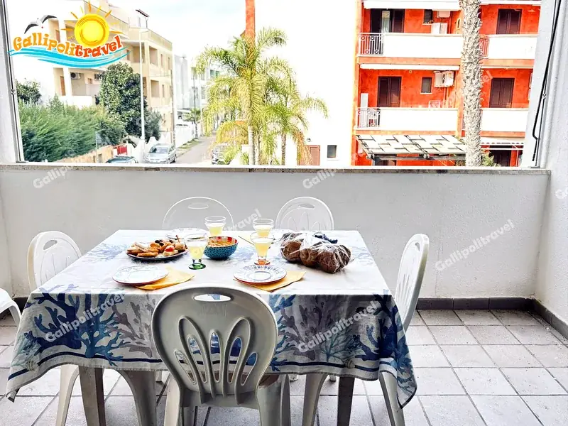 Balcone del Trilocale Mimosa a Baia Verde con tavolo apparecchiato e vista sulle palme