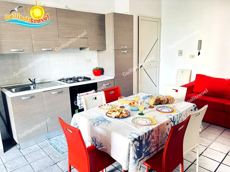 Cucina attrezzata con tavolo da pranzo e divano rosso del Trilocale Mimosa