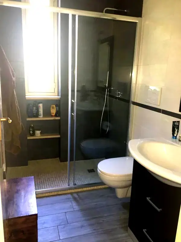 Bagno moderno del Trilocale Girasole con doccia scorrevole e piastrelle scure