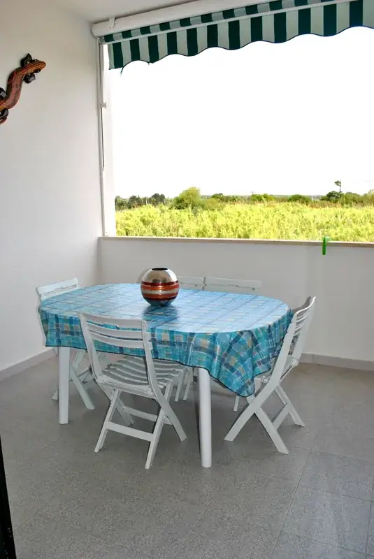 Balcone del Trilocale Girasole con tavolo azzurro e vista sulla campagna di Baia Verde