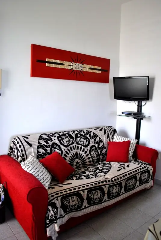 Soggiorno del Trilocale Girasole con divano rosso, quadro decorativo e TV